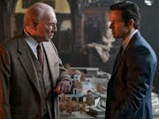 An older white man and another white man in sharp suits in a stately home, looking intensely at each other