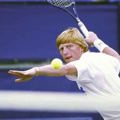 Blonde tennis played prepares to hit the ball with his racket in the air