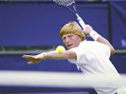 Blonde tennis played prepares to hit the ball with his racket in the air