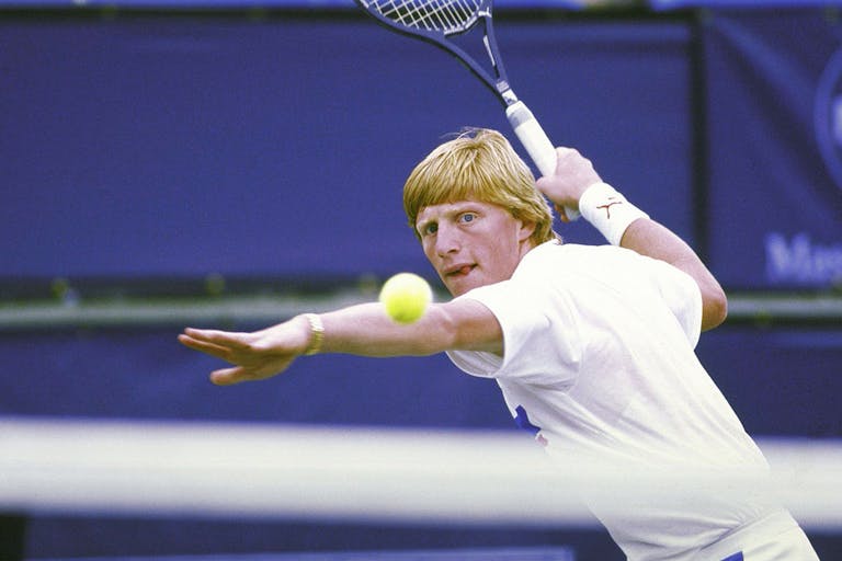 Blonde tennis played prepares to hit the ball with his racket in the air