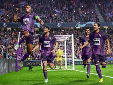 Game still of realistic male football players in purple kit running on the pitch celebrating with big crowds in the background