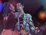 Game still of a young Black woman and a young white man playing guitar, sharing a microphone singing into it, sketchbook style animation