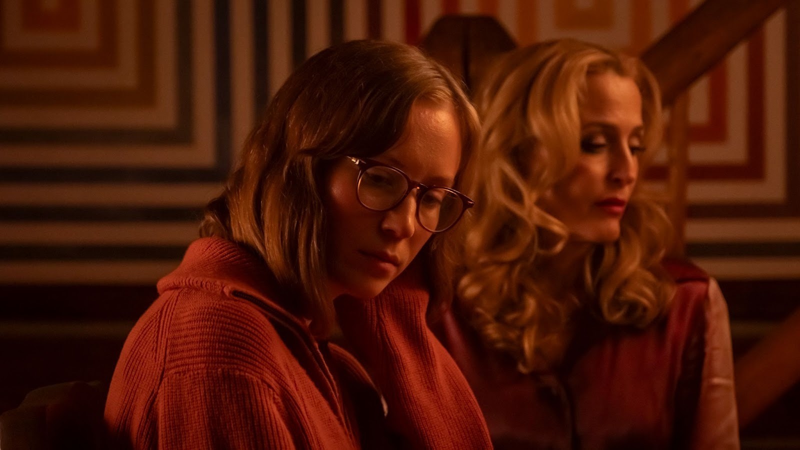 A young dark-haired woman with glasses, next to an older blonde woman, both in pink
