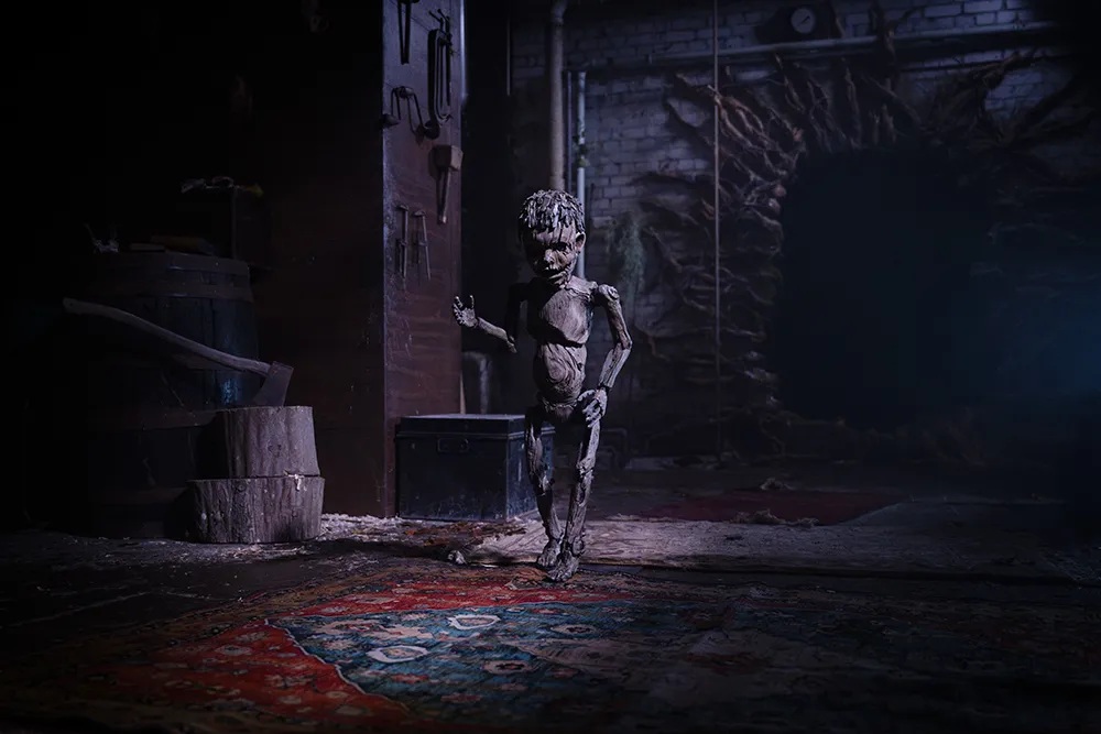A small wooden puppet standing upright in a dark room