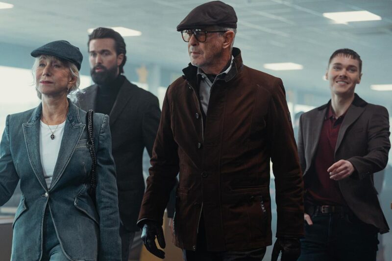 3 men and 1 women wearing dark suit jackets walking threateningly in a building