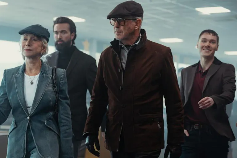 3 men and 1 women wearing dark suit jackets walking threateningly in a building