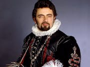 A white man with dark hair and facial hair wearing an Elizabethan ruffle and elegant black outfit