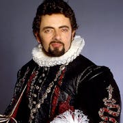 A white man with dark hair and facial hair wearing an Elizabethan ruffle and elegant black outfit