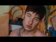 A young whit man with dark hair and bug tattoos on his chest