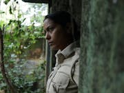 A young Indian policewoman looking contemplative in a moss covered stone doorway stepping out into greenery