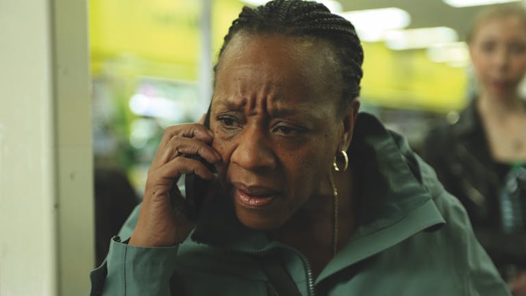 A middle aged Black woman on mobile phone looking distressed