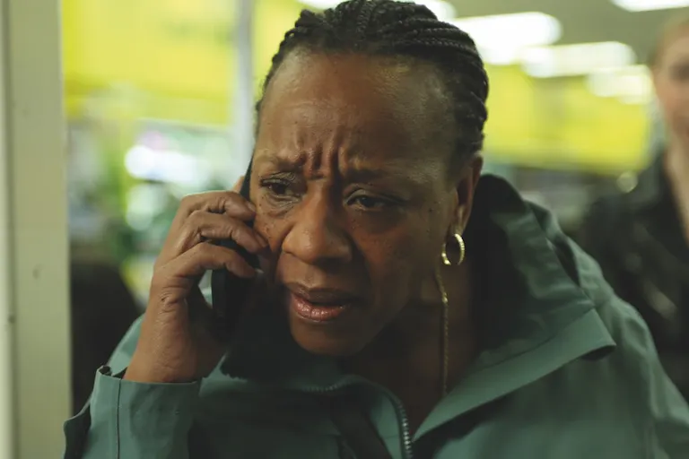 A middle aged Black woman on mobile phone looking distressed