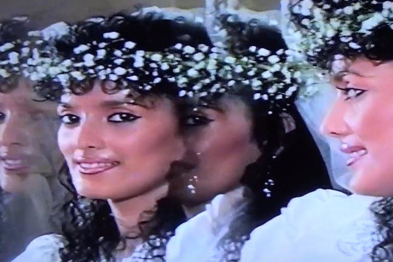 An Asian woman looking at a mirror where 3 reflections look back at hear. she is wearing a crown of flowers and possibly a wedding dress