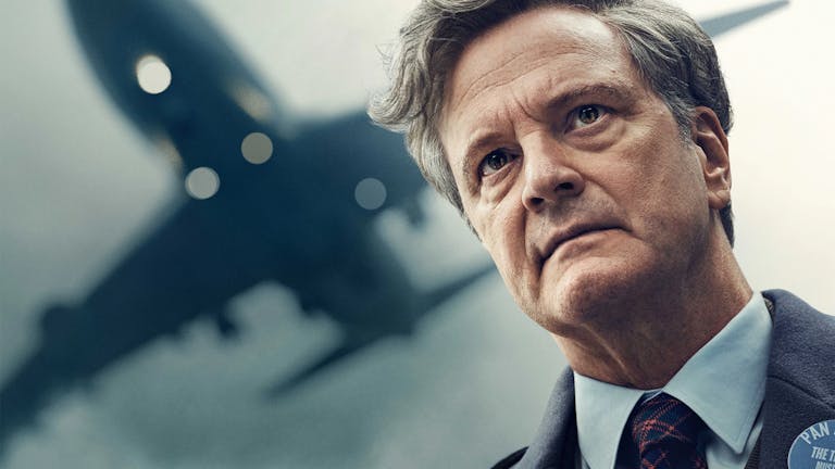 A middle aged white man with grey hair wearing a suit looking haunted as a plane flies overhead