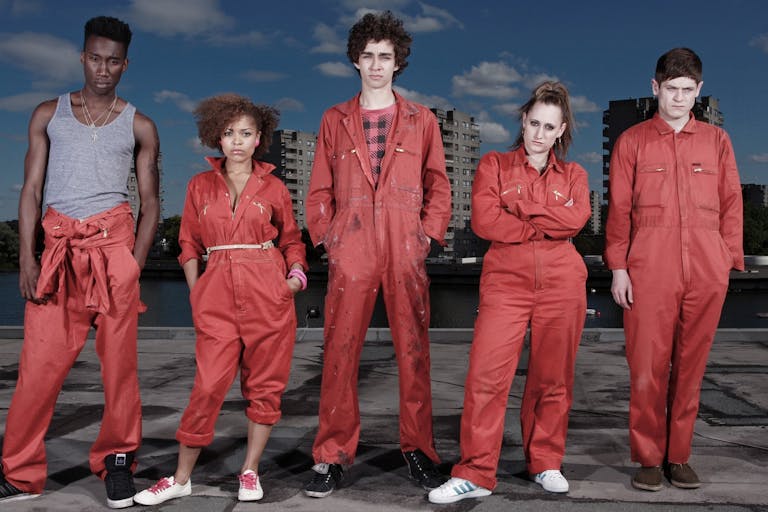 Five people in orange uniforms staring at the camera