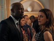 A black man and a white woman are talking and looking around the room