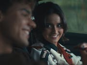 A young brunette woman sits in the car next to a young man smiling