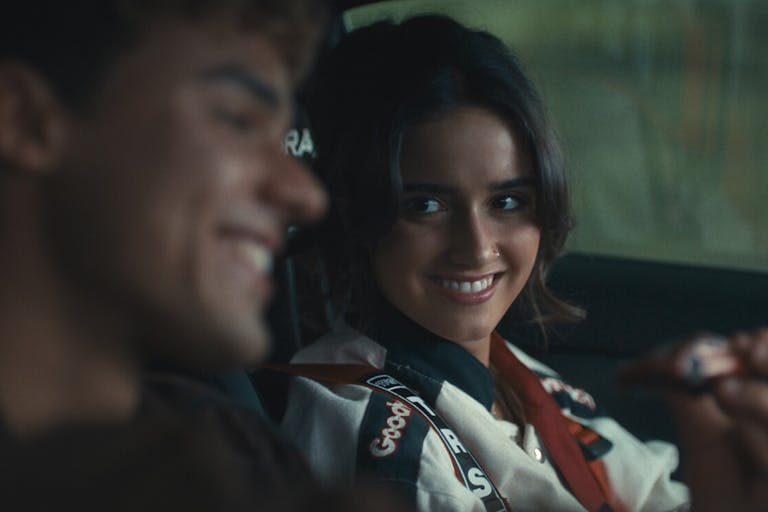 A young brunette woman sits in the car next to a young man smiling