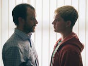 An older white man stands face to face with a young white man