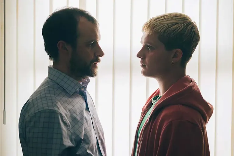 An older white man stands face to face with a young white man