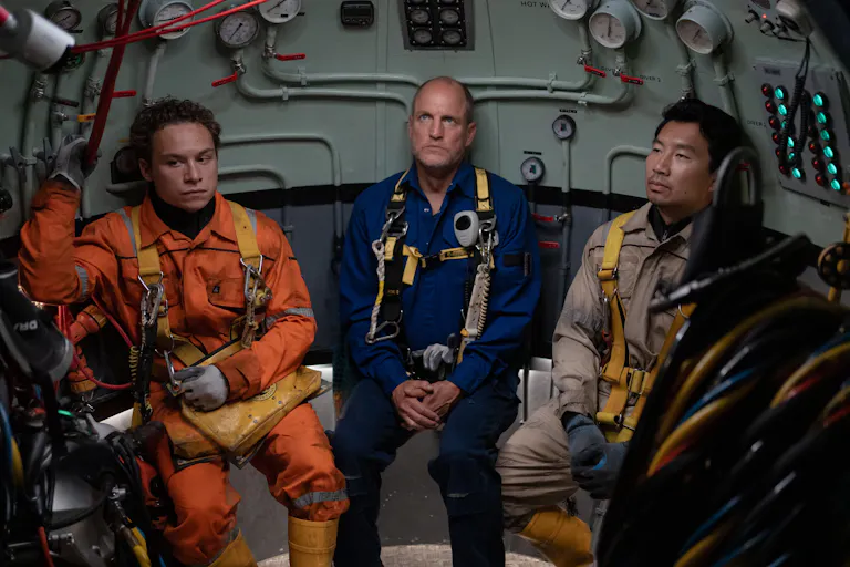 Three men in uniform sitting inside a submarine looking defeated