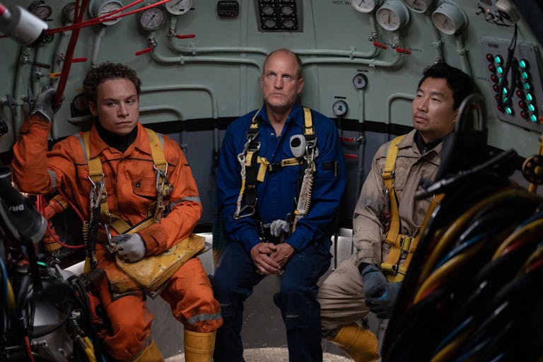 Three men in uniform sitting inside a submarine looking defeated