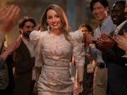 A young white woman walking between people as they clap for her