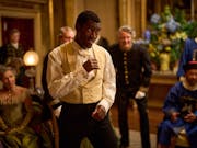 A young Black man in a Victorian suit in a fighting stance in a grand room with other Victorian people spectating