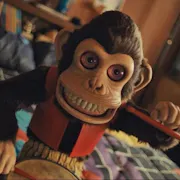 A demonic looking toy monkey playing a drum