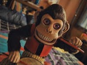 A demonic looking toy monkey playing a drum