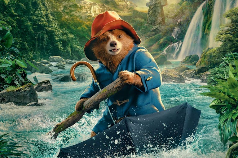 A CGI bear in blue coat and red hat, rafting on an open upturned umbrella down a river