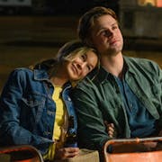 A white woman looking happy with her head resting on a young white man's shoulder