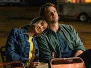 A white woman looking happy with her head resting on a young white man's shoulder