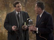 Two middle aged white man in smart suits holding an early 20th Century microphone