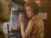 A white woman sits at a bar with a drink