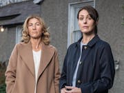 Two white women looking serious in front of a house