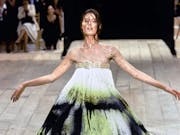 A woman model in an Alexander McQueen dress with belt at the top, sprayed with black and neon green paint