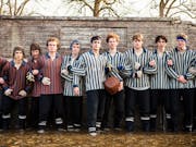A long line of young teen boys in striped 80s boarding school football uniforms linking arms