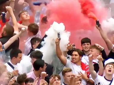 A group of majority young white men in England supporter football shirts letting off red and white flares