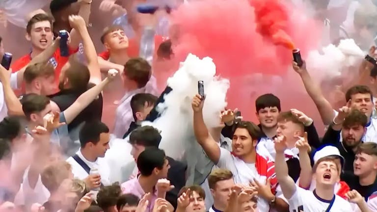 A group of majority young white men in England supporter football shirts letting off red and white flares