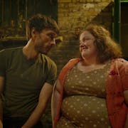 A white man looking serious at a white woman smiling strongly