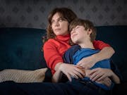 A young white woman cuddling a child looking content