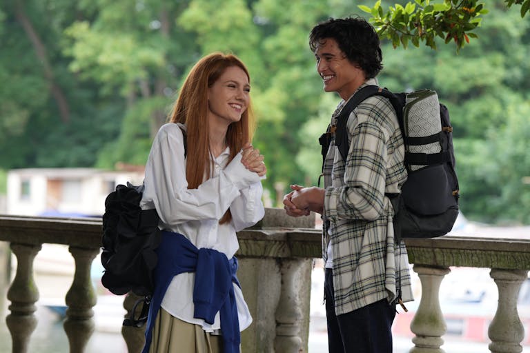 A white teen girl with red hair smiling widely with a brown teen boy