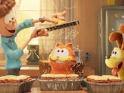 Colourful CGI animation of a white man grating cheese over a three trays of lasagne while an orange cat and yellow dog look on in delight