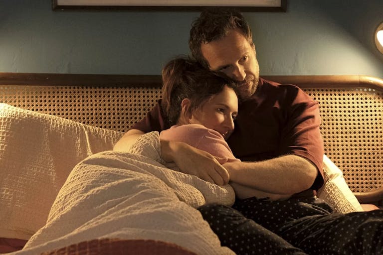 A white woman and man cuddle in bed