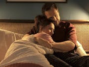 A white woman and man cuddle in bed