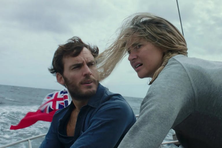 A white man and woman looking windswept and concerned on a sailboat