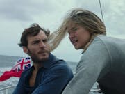 A white man and woman looking windswept and concerned on a sailboat
