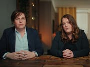 Two white women sitting at a table looking serious