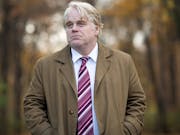 A middle aged white man in a suit with red striped tie walking through trees